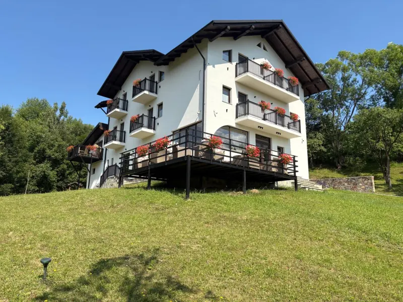 Casa albă pe deal, cu balcoane pline de mușcate și terasa pe stâlpi